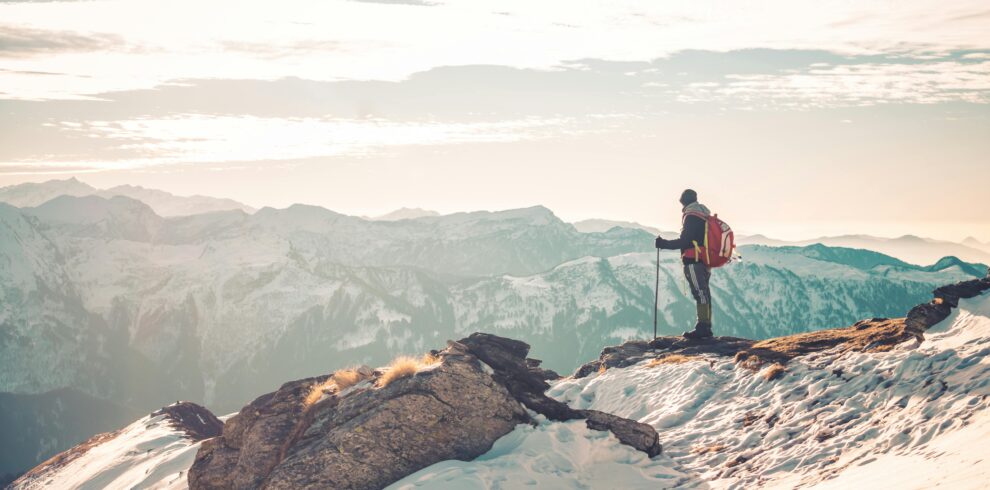 Person Standing on Top of Snow Covered Mountain